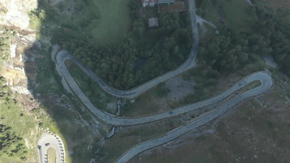 Aerial: top down view tailspin over winding mountain road on the Italian Alps alt