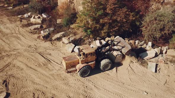 Professional Bulldozer With a Bucket is Spreading Sand Near the Stones alt