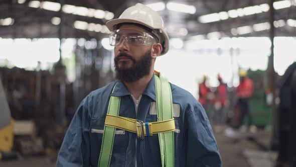 Male engineer worker wearing hardhat and protective eyeglasses walking in the factory