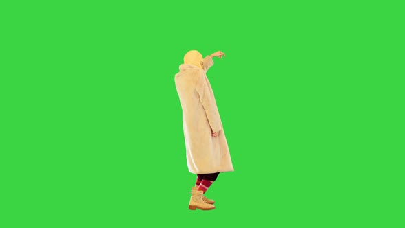 Young Daring Girl in Coat and Balaclava Dancing on a Green Screen Chroma Key