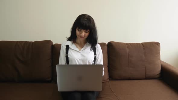 Young Woman Using Laptop at Home Sitting on Sofa alt
