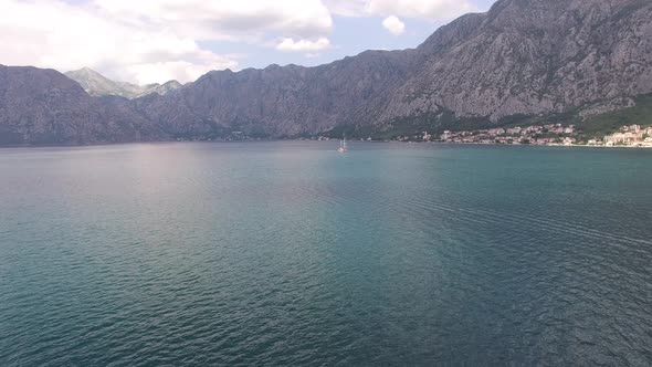 Sailboat Sails Along the Bay of Kotor Past the Prcanj Coast alt