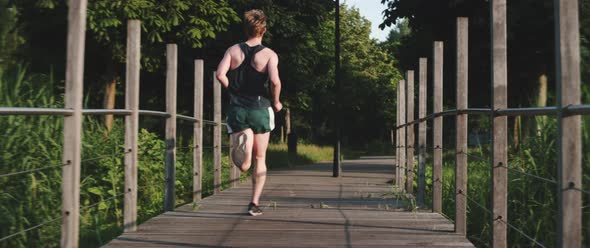 Man runs across a wooden bridge alt