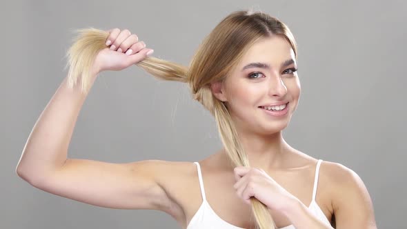 Pretty Girl Ties Up Hair and Smiling alt