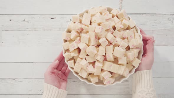 Flat lay. Step by step. Candy cane fudge cut in small cubes on a white serving dish alt