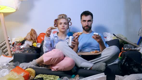 Couple sitting in the dirty room with garbage