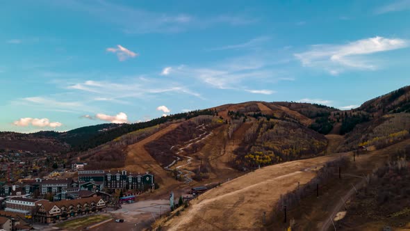 Aerial hyperlapse and cloudscape over a ski resort and mountain community in autumn alt