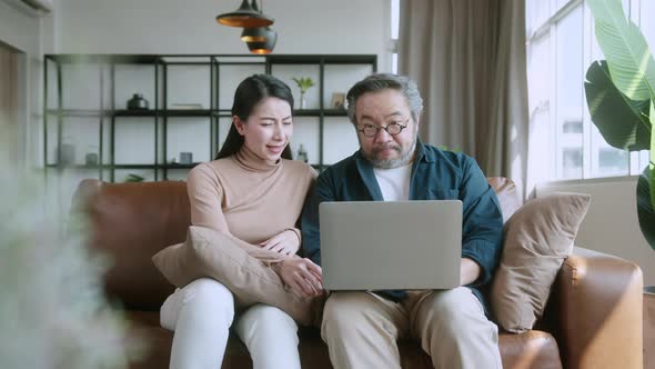 asian marry couple checking and calculate financial billing together on sofa