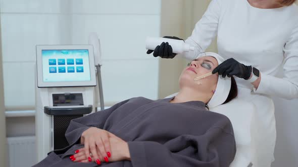 Cosmetologist is Preparing Face Skin of Female Patient for Photo Rejuvenation By New Apparatus alt