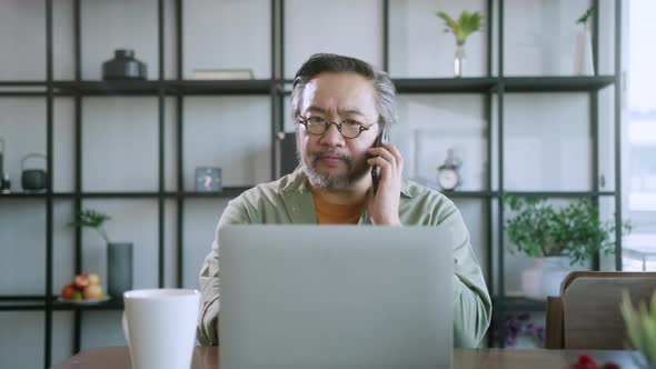 asian male dad using laptop and conversation on smartphone remotely distance working