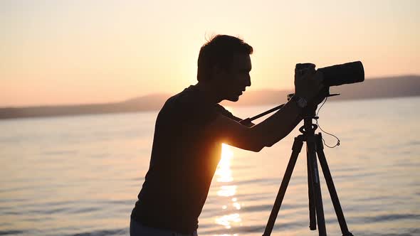 A Young Man With Camera Enjoy Taking Video On The Sunset In Lake Bracciano, Italy - Wide Shot alt