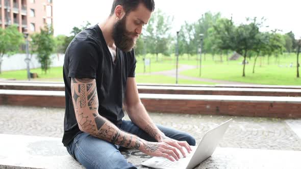 young beautiful smart creative business man sitting outdoor using personal computer alt
