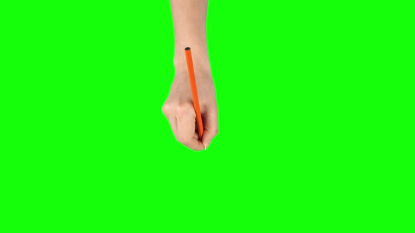 Female Hand with Orange Pencil Is Writing on Green Screen Background. Close Up alt