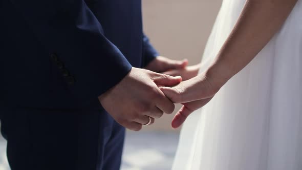 Bride and groom holding hands for their wedding, close up
