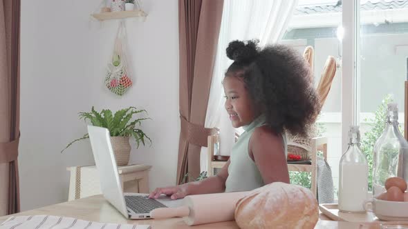 Cute African American little girl watching web class lesson by laptop computer. Children education.