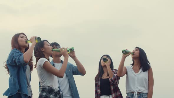 Group of Asia best friends teenagers dancing and drinking have fun salute toast of bottle beer.