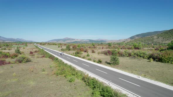 Empty Asphalt Road on the Plateau Between Green Fields Highland Way Aerial View alt