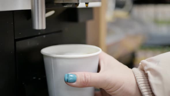 Female Hand Removes a Full Glass of Cappuccino From the Coffee Machine