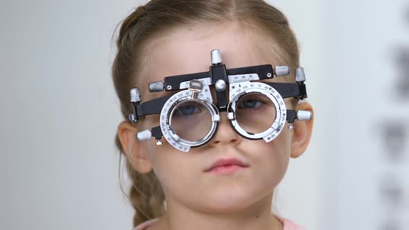 Male Ophthalmologist Choosing Eyeglasses Lens for Small Girl Wearing Phoropter alt