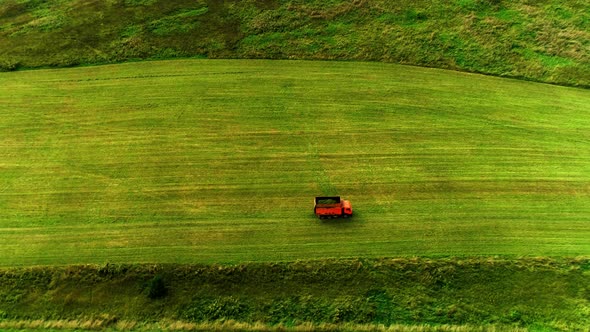 Orange Dump Truck Driving In The Green Field