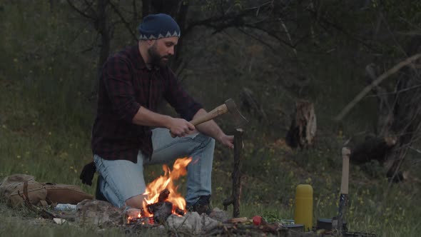 Slow Motion of Hiker Traveller Starts Campfire Chops Wood with Axe Near Blazing Flame of Bonfire in