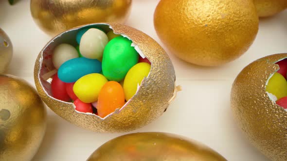 Golden Decorative Easter Eggs Filled with Colorful Candies on Wooden Table Close Up