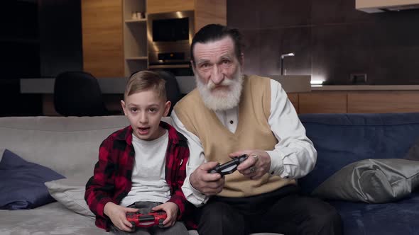 Senior Man and His Serious Grandson which Playing Together Video Game  alt