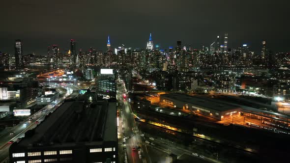 An aerial view from over Long Island City, New York at night. The drone camera slowly truck left and alt