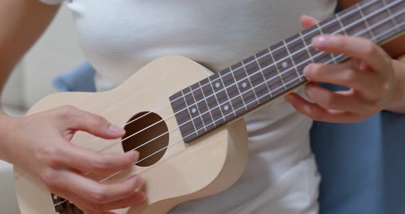 Woman play ukulele at home alt