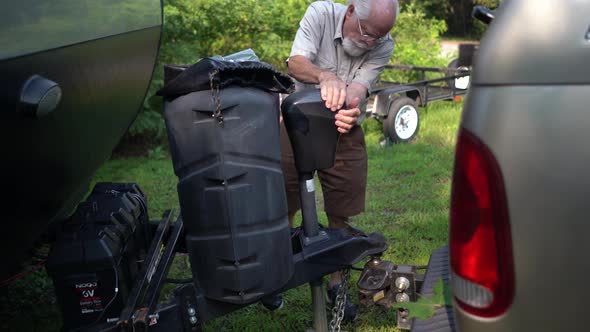 Elderly man adjusts RV hookup while talking to someone and motioning how far away it was. alt
