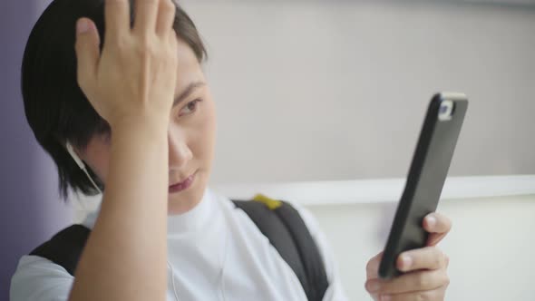 Portrait of asian woman with earphone listening music and using smartphone for chatting