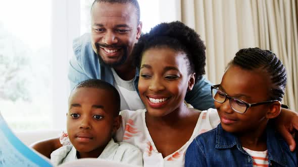 Parents and kids sitting together on sofa with photo album alt