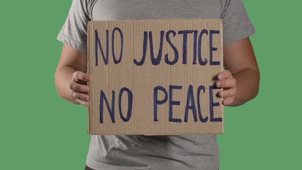 Man Holds in Front of Him a Poster From a Cardboard Box with the Words NO JUSTICE NO PEACE. Concept alt