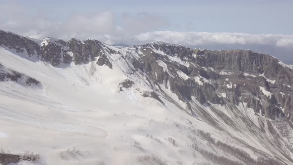 Aerial view of snowy peaks of rocky Caucasus mountains, Krasnaya Polyana, Sochi, Russia. Blue sky