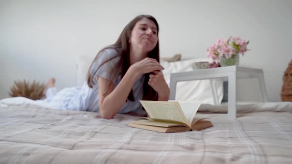 A Woman Lies on the Bed and Calls the Cat alt