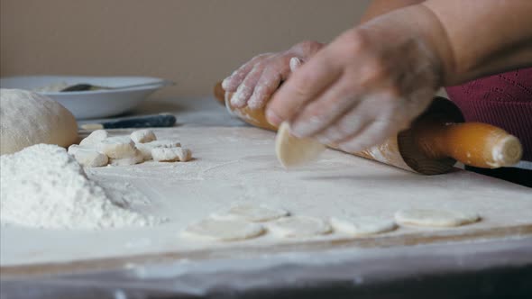 Close-up Hands of Senior Female Is Rolling a Dough for Dumplings at Home Kitchen