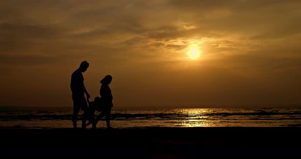 Silhouette a Pregnant Woman with Her Family Walking Along the Seashore Hair Blowing in the Wind alt
