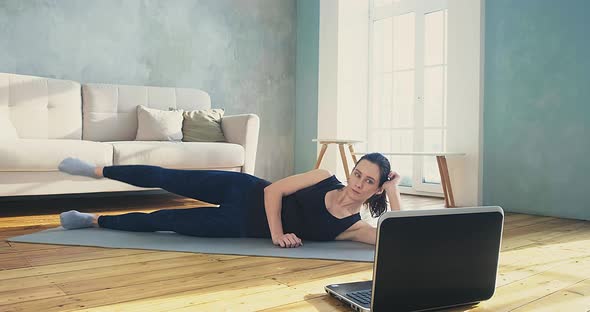 Woman Does Supine Side Leg Raises Watching Online Training alt