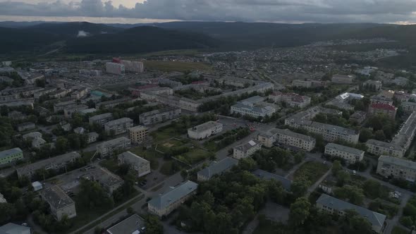 Aerial view of city with hight and low buildings. Cars are driving. Evening