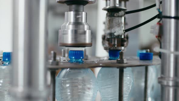 Water Factory Industrial Machine Puts Caps on Plastic PET Bottles with Water Close Up