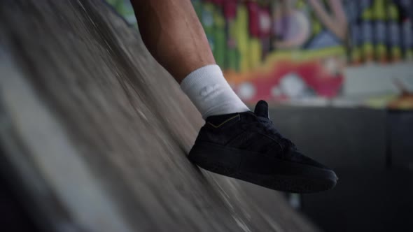 Unknown Man Having Break After Riding on Skate Board at Skatepark with Graffiti alt