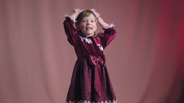 Little Girl in Vintage Burgundy Dress is Dancing Rejoicing Making Funny Faces