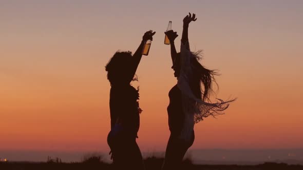 Silhouettes of Women Dancing at Beach Party at Sunset