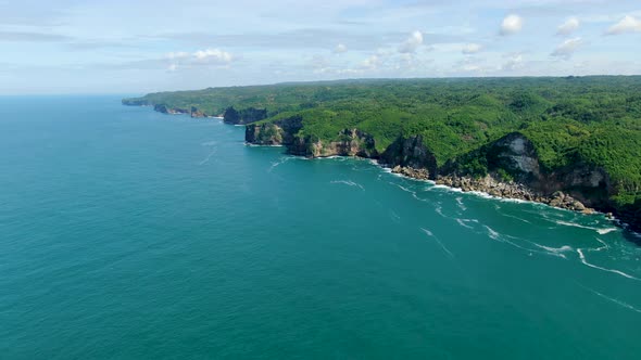 Aerial panorama stunning Kesirat, Java coast cliffs washed by calm ocean waves alt