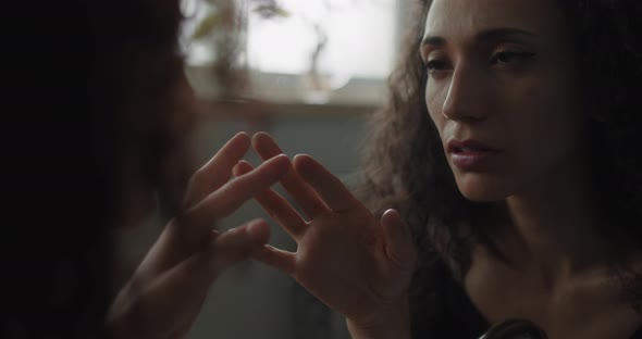 Woman touching reflection in the mirror alt