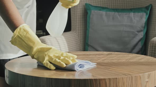 Gloved Hands of Housekeeper Cleaning Table in Hotel Room alt