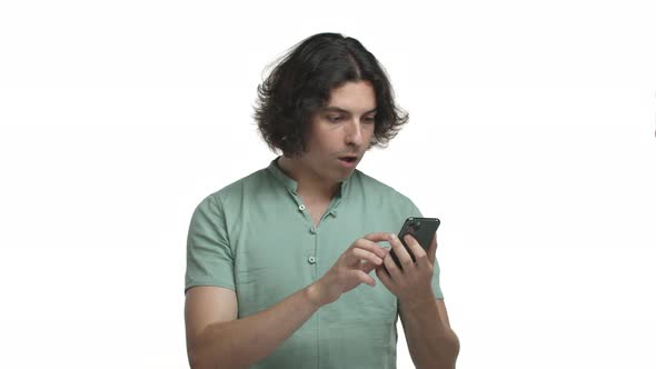 Video of Attractive Hispanic Man with Long Dark Hair Looking at Smartphone and Shopping Online alt