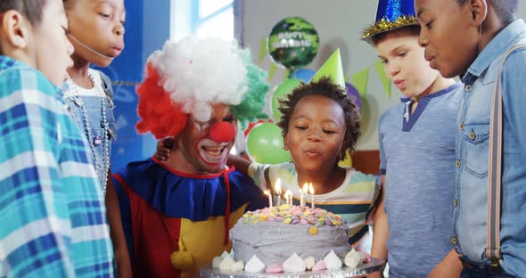 Kids with clown blowing candles on cake during birthday party 4k alt