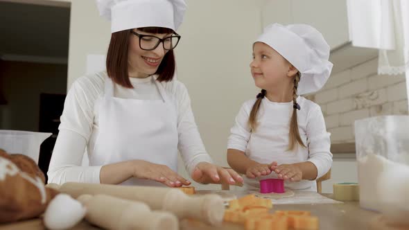 Adorable Little Girl And Her Caucasian Mom in Hats of Chef and Apron Makes Dough Figurines alt