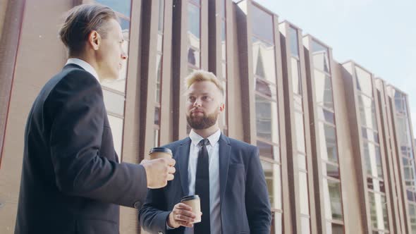 Confident businessman and his colleague in front of modern office building. alt
